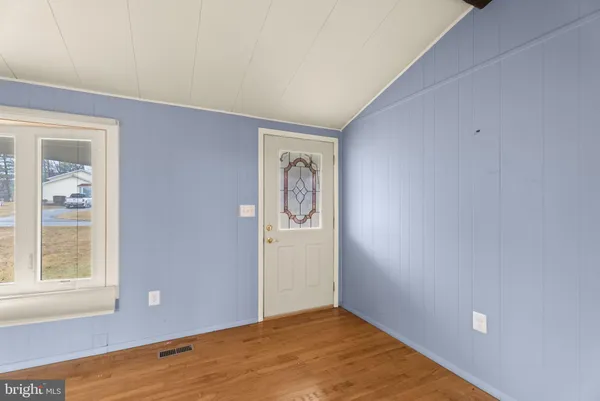 a view of an empty room with window and wooden floor