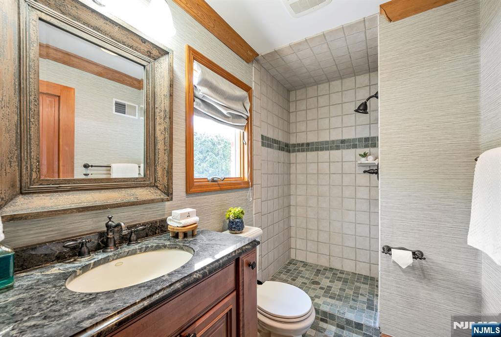 411 Snyder Road Wyckoff, NJ 07481 - Photo 16 of 36 a bathroom with a granite countertop toilet a sink a mirror a window and a shower