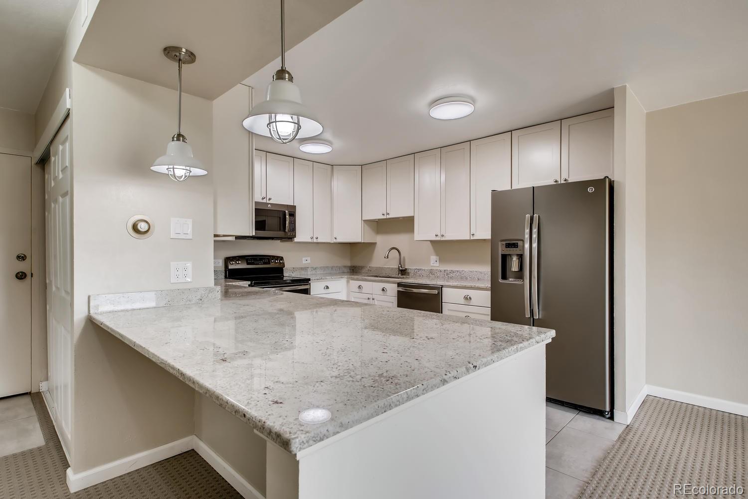 9340 Center Avenue, Unit 6B Denver, CO 80247 - Photo 15 of 40 a kitchen with stainless steel appliances granite countertop a refrigerator a sink a stove a microwave and island
