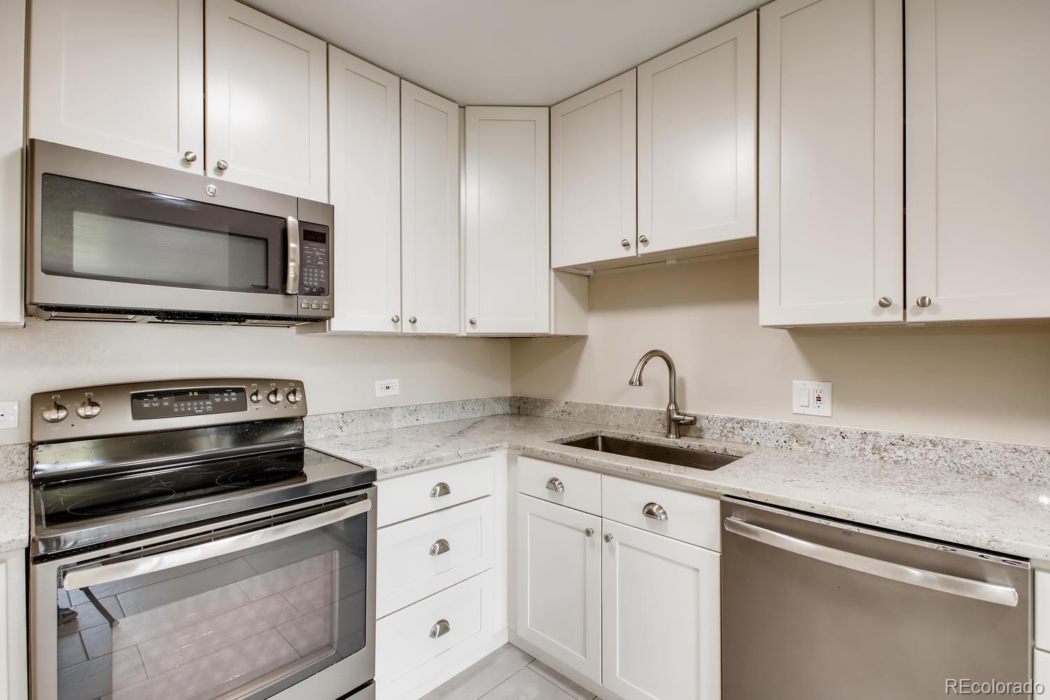 9340 Center Avenue, Unit 6B Denver, CO 80247 - Photo 17 of 40 a kitchen with granite countertop white cabinets and stainless steel appliances