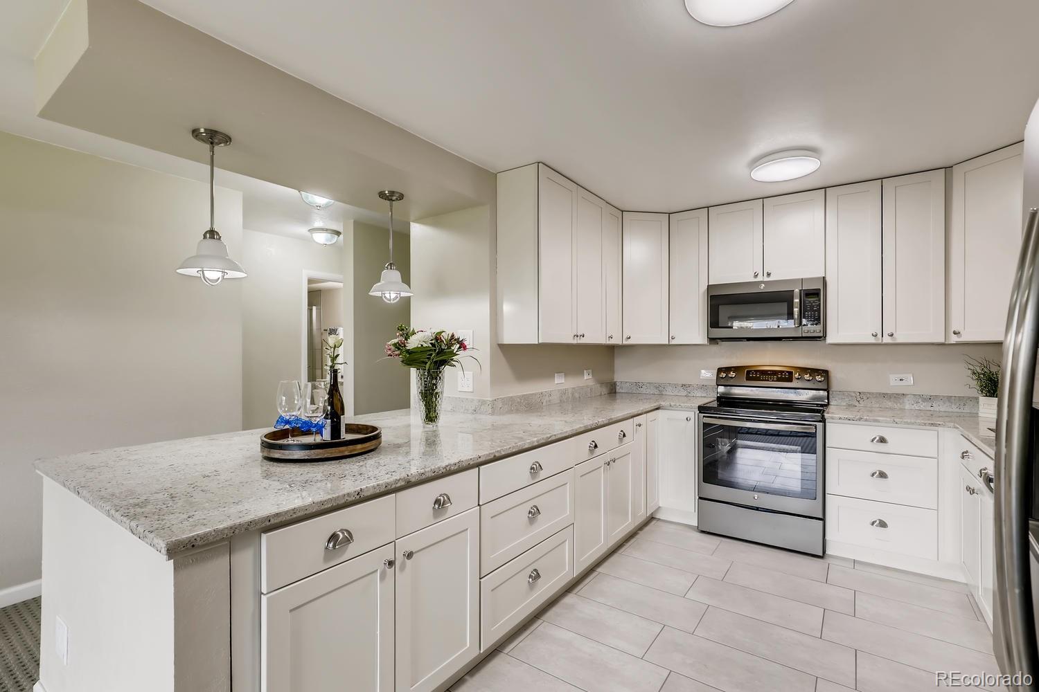 9340 Center Avenue, Unit 6B Denver, CO 80247 - Photo 18 of 40 a kitchen with white cabinets and appliances