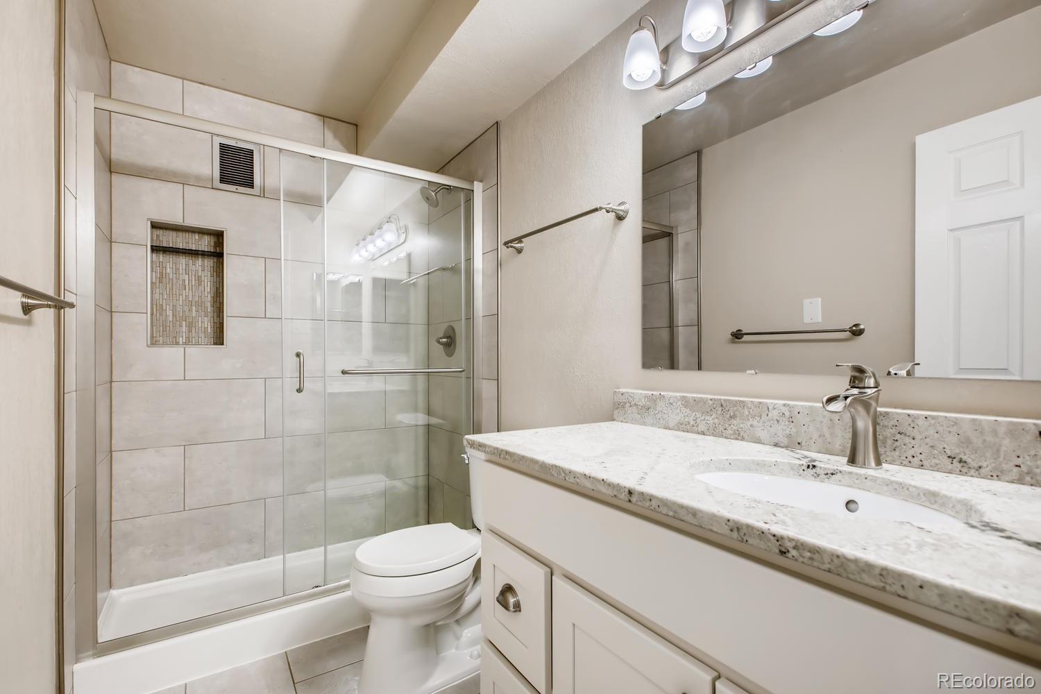 9340 Center Avenue, Unit 6B Denver, CO 80247 - Photo 22 of 40 a bathroom with a granite countertop sink toilet and shower