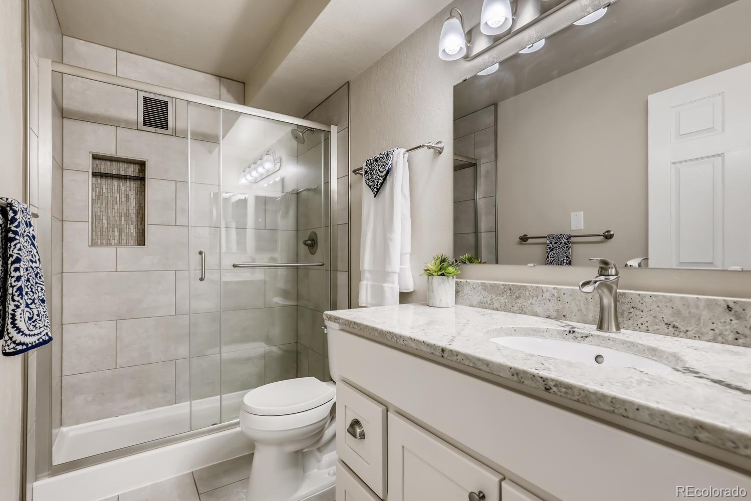 9340 Center Avenue, Unit 6B Denver, CO 80247 - Photo 24 of 40 a bathroom with a granite countertop sink toilet and shower
