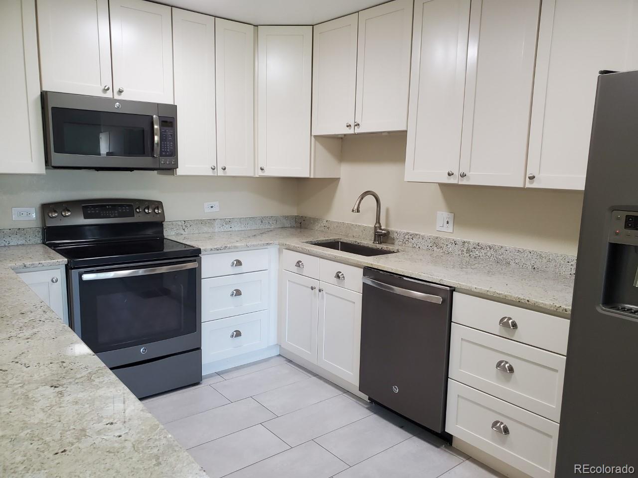 9340 Center Avenue, Unit 6B Denver, CO 80247 - Photo 28 of 40 a kitchen with granite countertop white cabinets and stainless steel appliances