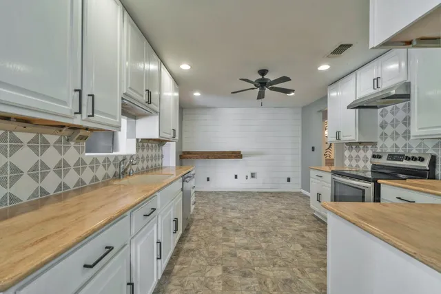 a kitchen with granite countertop white cabinets and white stainless steel appliances