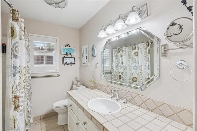 a bathroom with a granite countertop sink mirror vanity and toilet