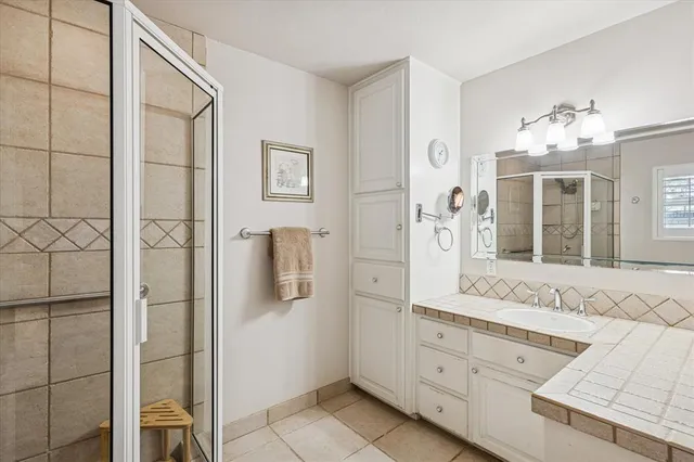 a spacious bathroom with a granite countertop sink a mirror and shower