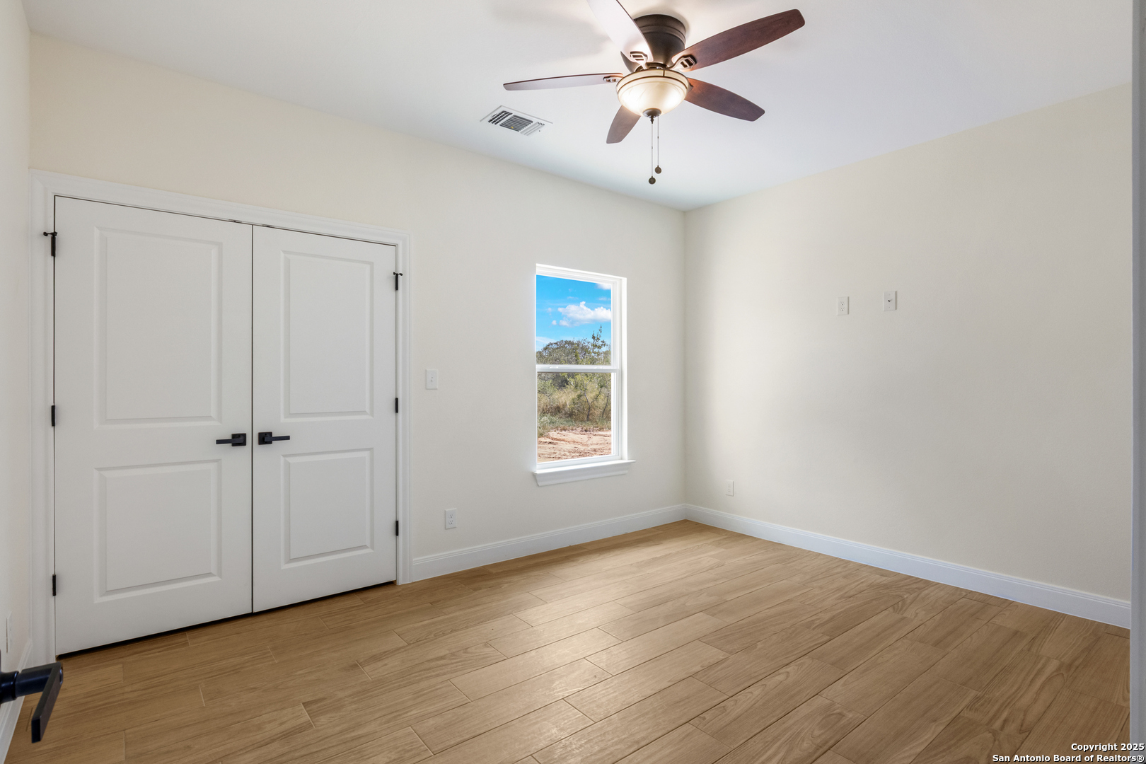 32 Trophy Lane Poteet, TX 78065 - Photo 12 of 47 a view of an empty room with a window and wooden floor
