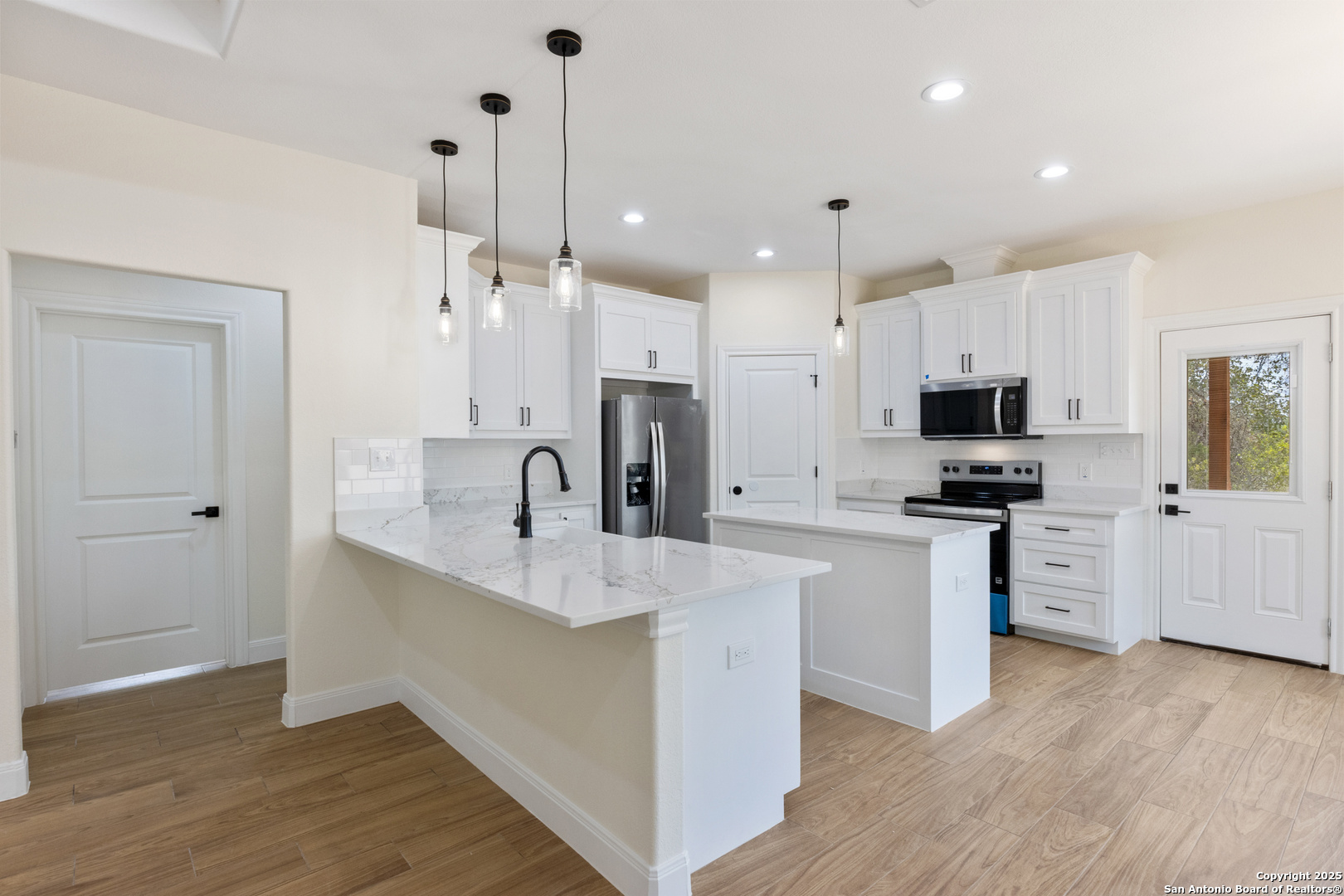 32 Trophy Lane Poteet, TX 78065 - Photo 7 of 47 a large kitchen with stainless steel appliances kitchen island granite countertop a stove a sink a refrigerator and white cabinets with wooden floor