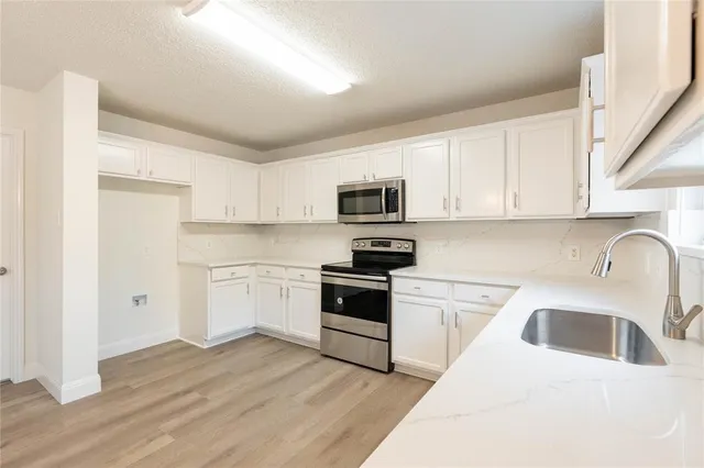a kitchen with a sink white cabinets and stainless steel appliances