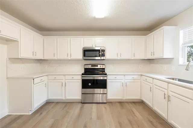 a white kitchen with granite countertop stainless steel appliances