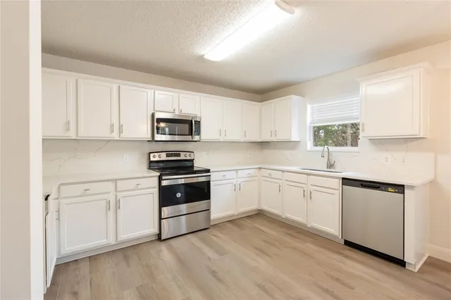 a kitchen with granite countertop white cabinets and white appliances
