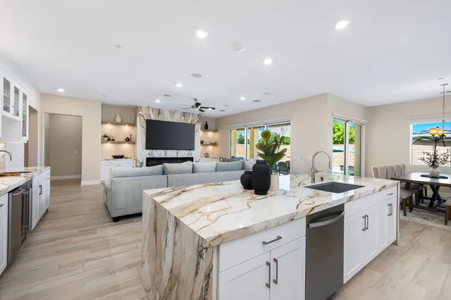 a room with kitchen island stainless steel appliances a sink stove and wooden floor
