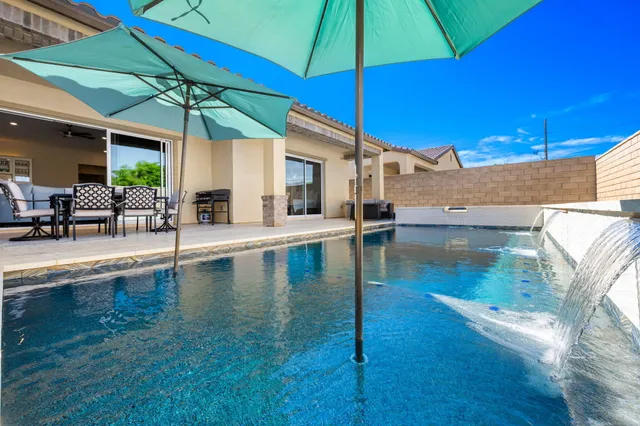 a view of a patio with swimming pool table and chairs under an umbrella