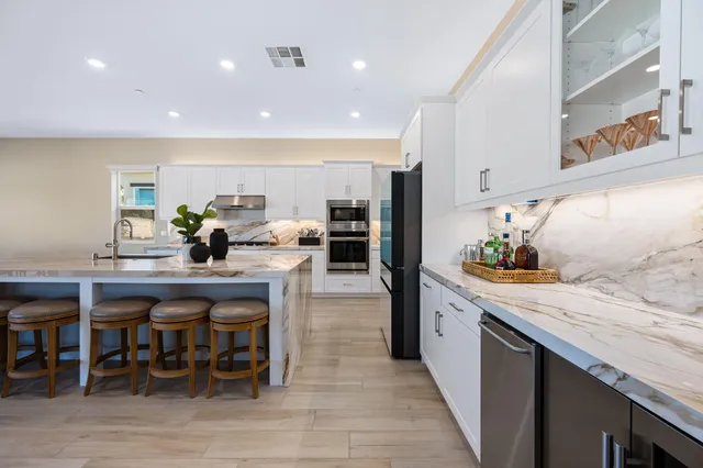a kitchen with stainless steel appliances granite countertop table chairs sink and cabinets