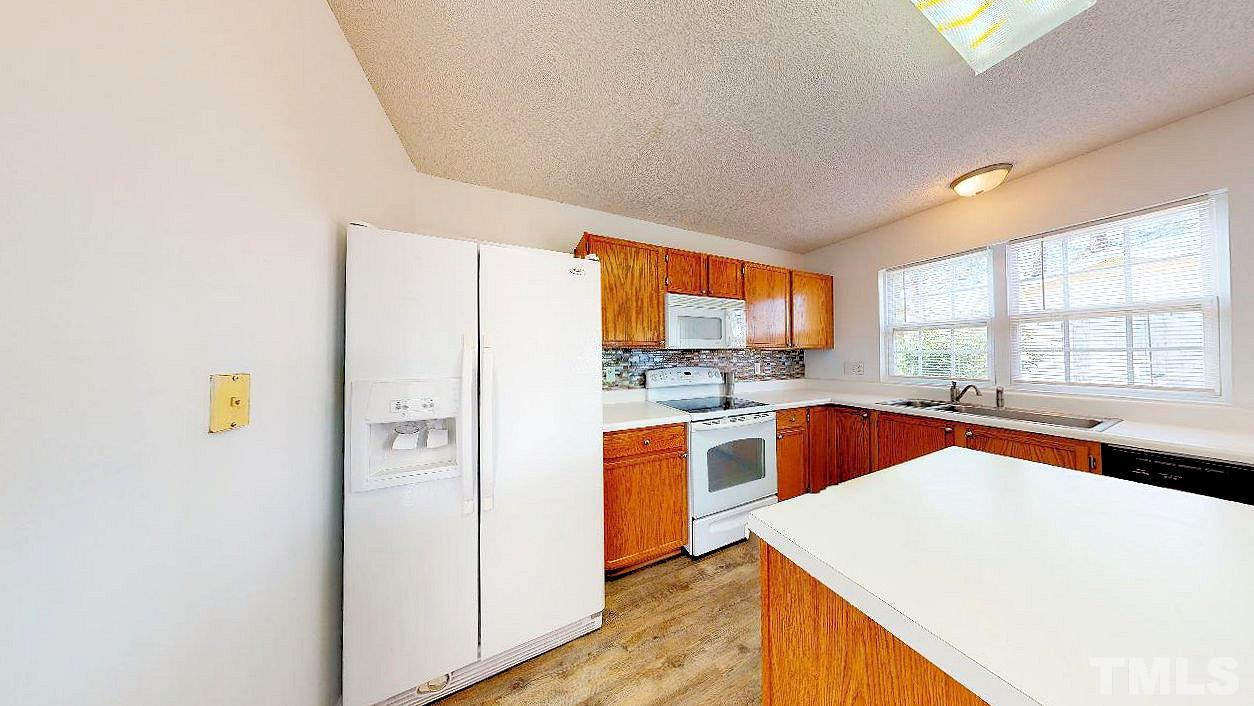 2901 Tuckland Drive Raleigh, NC 27610 - Photo 6 of 28 a kitchen with stainless steel appliances a refrigerator a sink a stove and white cabinets with wooden floor