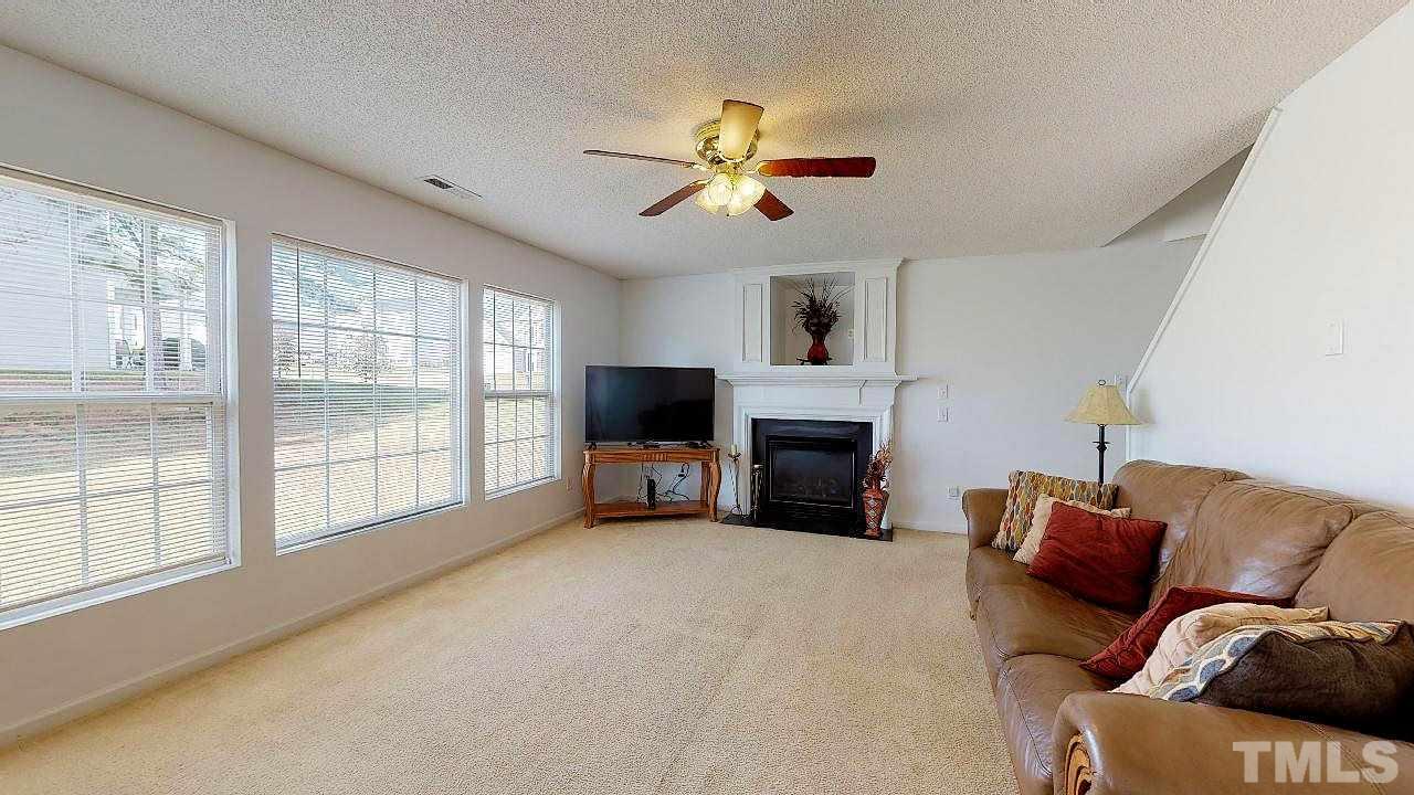 2901 Tuckland Drive Raleigh, NC 27610 - Photo 10 of 28 a living room with furniture a fireplace and a large window