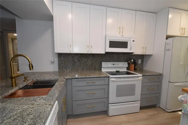 a kitchen with granite countertop white cabinets and white appliances