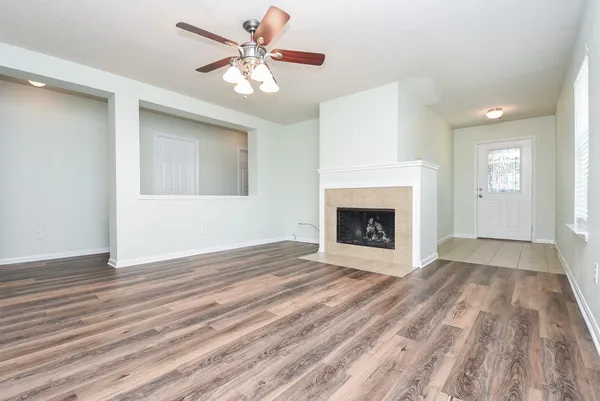 a view of an empty room with wooden floor a fireplace and a window