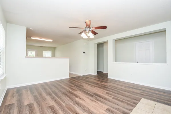 a view of empty room with wooden floor and fan