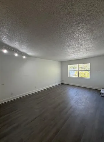 a view of empty room with wooden floor and window