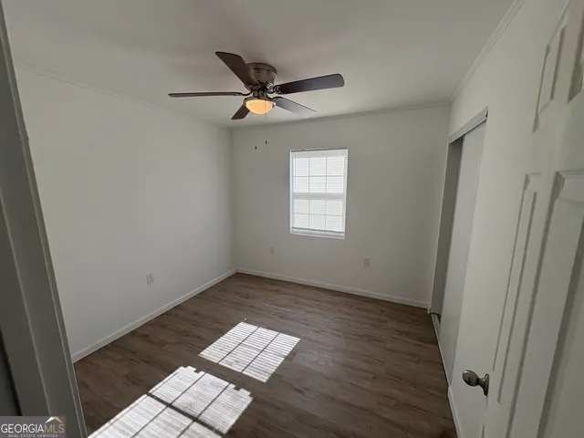 an empty room with wooden floor fan and windows