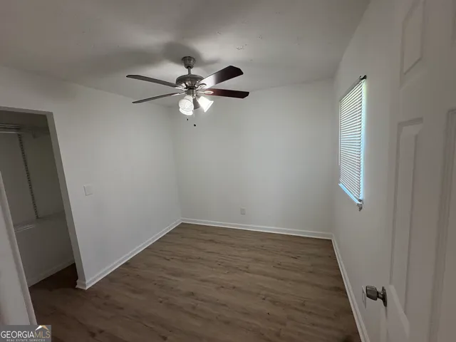an empty room with wooden floor fan and window