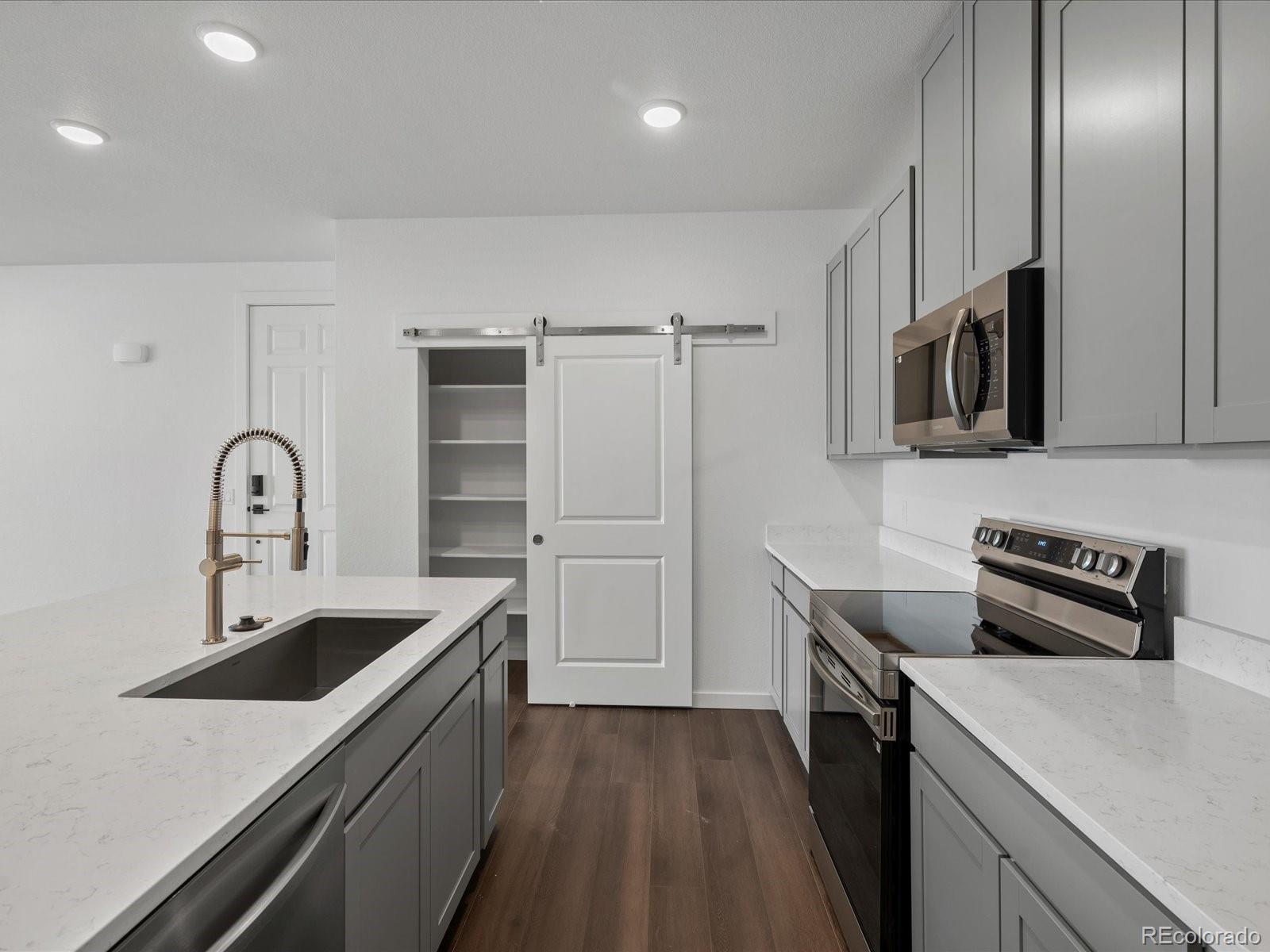6153 North Ceylon Street, Unit 304 Denver, CO 80249 - Photo 7 of 24 a kitchen with stainless steel appliances a sink a stove and cabinets