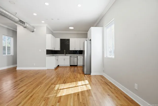 a view of a kitchen with wooden floor electronic appliances and stairs