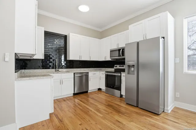 a kitchen with a refrigerator sink and white cabinets