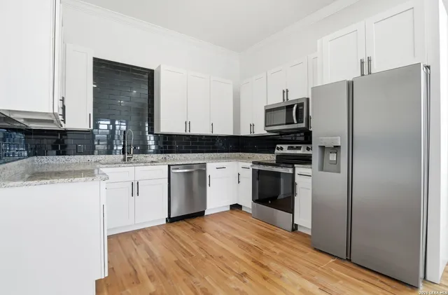 a kitchen with granite countertop a refrigerator stove and sink