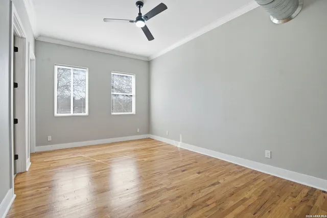 a view of empty room with wooden floor and fan