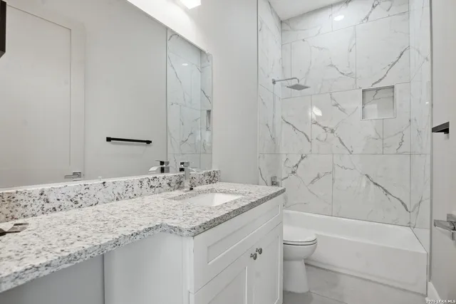 a bathroom with a granite countertop sink a toilet and bathtub
