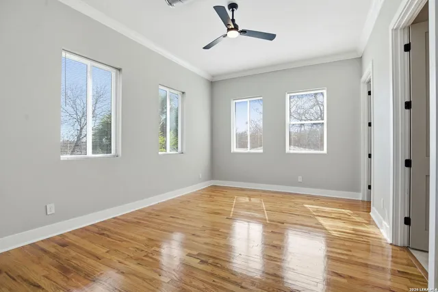 a view of empty room with wooden floor and fan