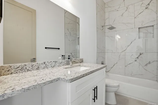 a bathroom with a granite countertop sink a toilet and bathtub