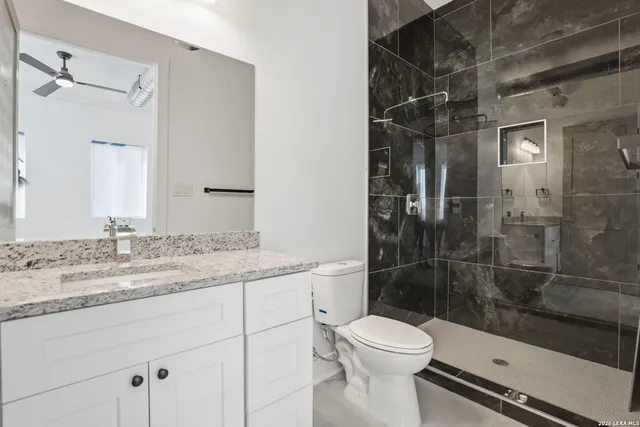 a bathroom with a granite countertop sink a toilet and shower