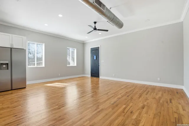 a view of an empty room with a window and wooden floor