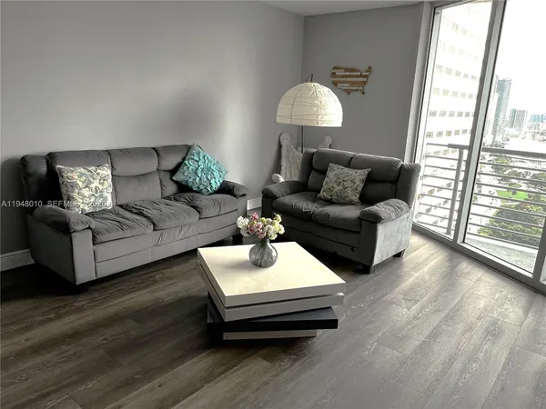 a living room with furniture wooden floor and a large window