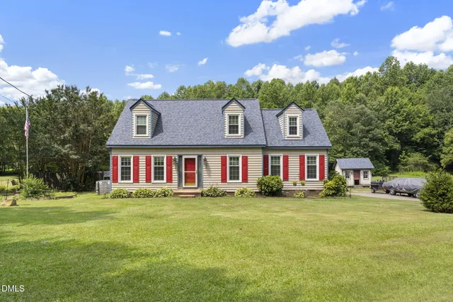 a view of a house with a big yard and large trees