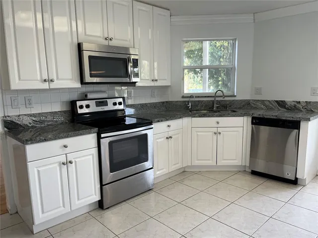 a kitchen with cabinets stainless steel appliances and sink