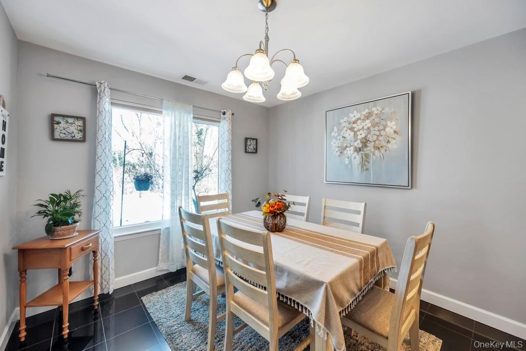 114 Birchwood Road Coram, NY 11727 - Photo 8 of 24 a dining room with wooden floor a chandelier a wooden table and chairs