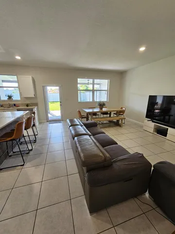 a living room with couches and kitchen view with wooden floor