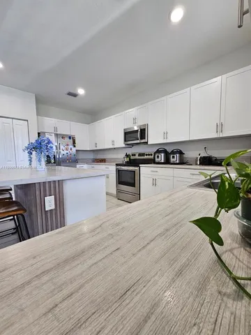 a kitchen with granite countertop a stove a sink dishwasher and a refrigerator with wooden floor