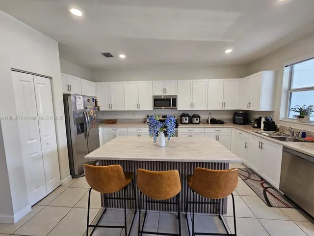 a kitchen with stainless steel appliances granite countertop a refrigerator a sink a stove a microwave a dining table and chairs