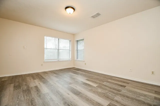 an empty room with wooden floor and windows