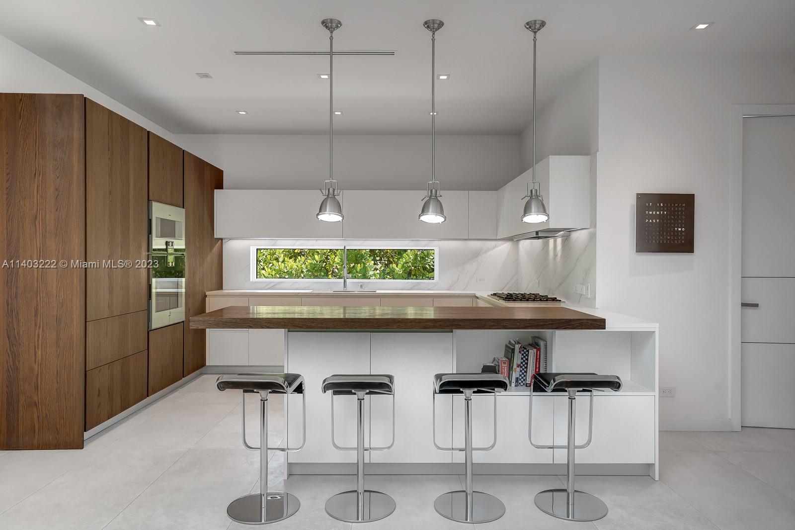 141 Harbor Drive Key Biscayne, FL 33149 - Photo 19 of 56 a kitchen with stainless steel appliances kitchen island a table chairs in it and wooden floors