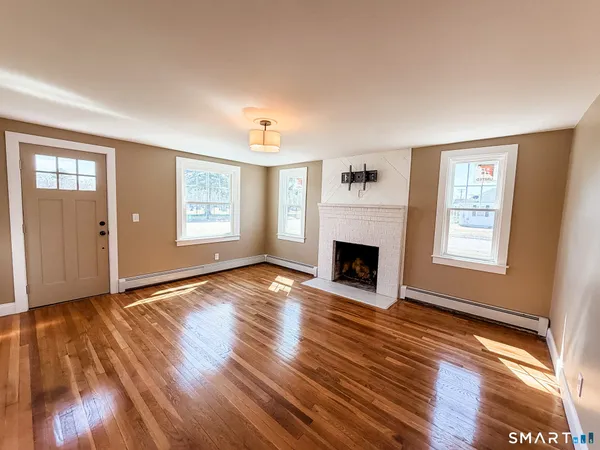 an empty room with windows a fireplace and wooden floor