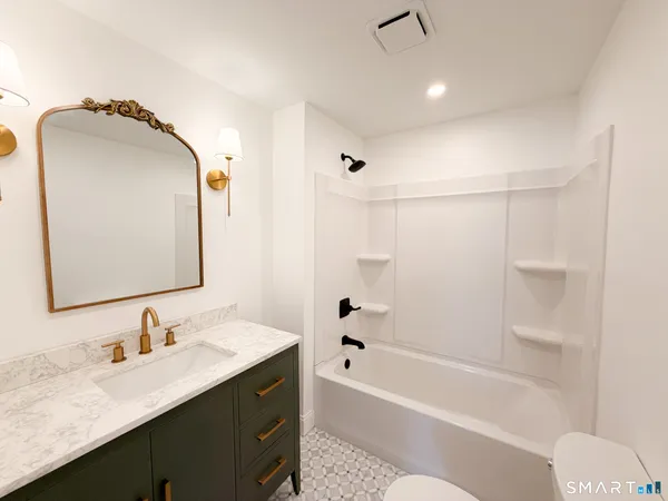 a bathroom with a granite countertop sink mirror and a bathtub