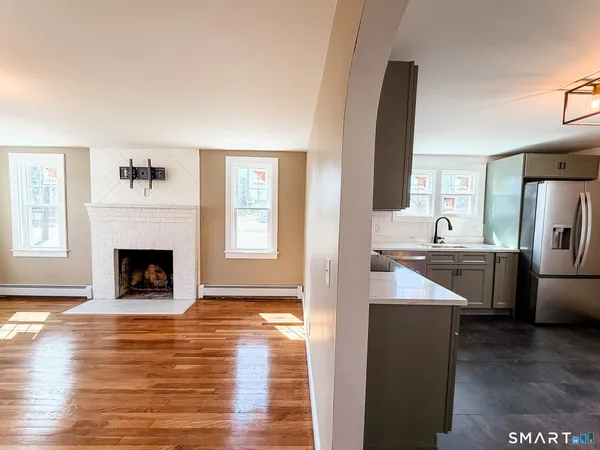 a living room with stainless steel appliances kitchen island a fireplace and wooden floor
