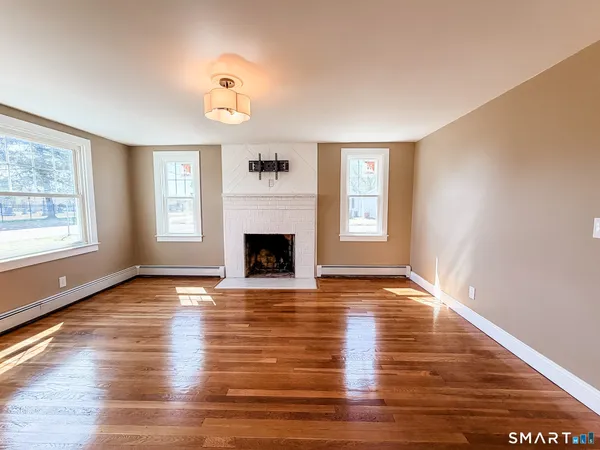 a view of empty room with wooden floor and fireplace